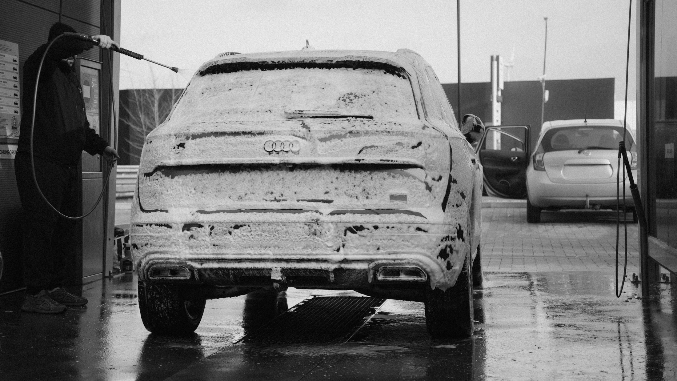 A dark vehicle covered in foam during an exterior wash